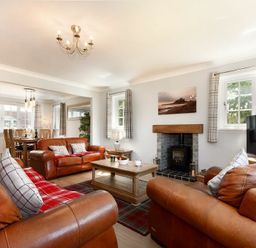A living room with brown leather sofas a wooden coffee table a fireplace and a television at Castlewood in Bamburgh