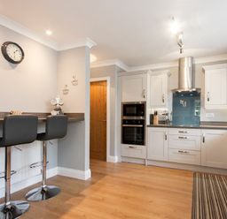 A kitchen with two bar stools at a counter and cabinets with appliances at Castlewood in Bamburgh
