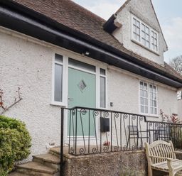 The exterior of a house with a green front door black metal railings and outdoor seating at Rosedale Lodge in Alnmouth