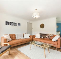 A living room with two brown leather sofas a glass coffee table and an armchair at Spuggies Rest in Embleton