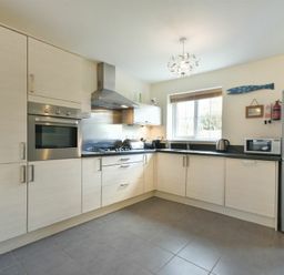 A kitchen with built in oven stove refrigerator microwave kettle and cupboards at Coast View in Beadnell