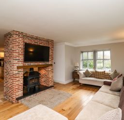 A living room with two sofas a brick fireplace and a mounted TV at The Old Stables in Bamburgh