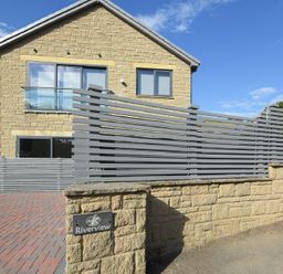 A stone house with large windows and a gray wooden fence at Riverview in Alnmouth