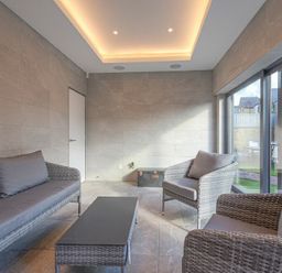 A sitting area with gray cushioned wicker furniture and a black coffee table by large windows at Riverview Alnmouth