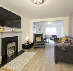 A living room with a fireplace television armchair sofa and dining area at Coastal View in Seahouses