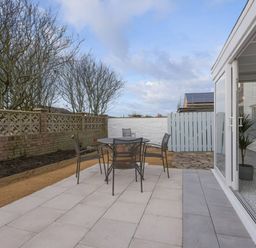 A garden with outdoor seating and a fence at Dell Point in Beadnell