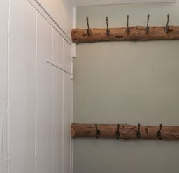 A wall with two wooden coat racks mounted in a room at Five Bells Cottage in Alnmouth