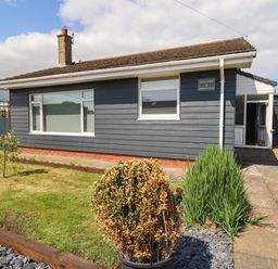 A single-story house with blue siding and white trim with a front garden and walkway at Willow in Beadnell