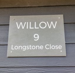 A house sign with text Willow 9 Longstone Close on a dark wall at Willow in Beadnell
