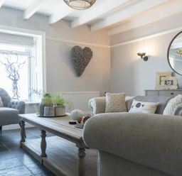 A living room with armchairs sofas a wooden coffee table and wall decoration at Creel Cottage Craster