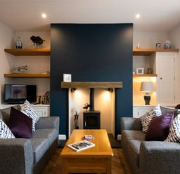 A living room with two gray sofas and a wooden coffee table facing a fireplace with shelves on either side at Wisteria Cottage in Warkworth