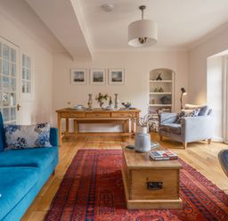 A living room with a blue sofa and dining table at Westhill House in Warkworth