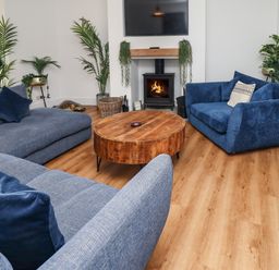 A living room with blue sofas a round wooden coffee table a fireplace and several potted plants at Muscle Shoals in Seahouses