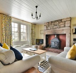 A living room with two sofas a wooden coffee table a fireplace and floral curtains at Sandpiper Cottage Low Newton-by-the-Sea