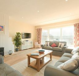 A living room with sofas and a wooden coffee table near large windows at The Boathouse (Alnmouth) in Alnmouth