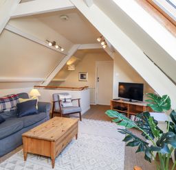 A living room with a sofa armchair wooden coffee table and television at Coach House Alnmouth