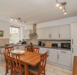 A kitchen with wooden dining table and chairs and light grey cabinets at Avocet Cottage in Bamburgh