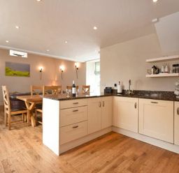 A kitchen and dining area with wooden chairs a table and cabinets at High Tide in Newton-by-the-Sea