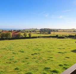 A view of houses and greenery with the ocean in the background at Links View in Embleton