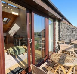 A balcony with a wooden table and chairs at Links View in Embleton