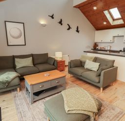 A living room with seating and kitchen counter at Links View in Embleton