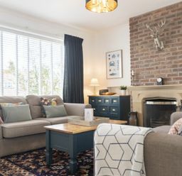 A living room with sofas a coffee table and a brick fireplace at Sea Croft in Beadnell