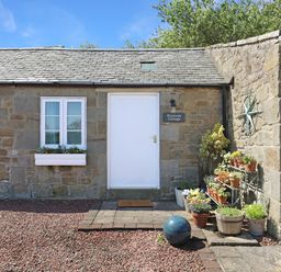 An entrance with a door and flower pots at Plumtree Cottage in Alnmouth