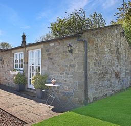 An outdoor patio area with a table and chairs at Plumtree Cottage in Alnmouth