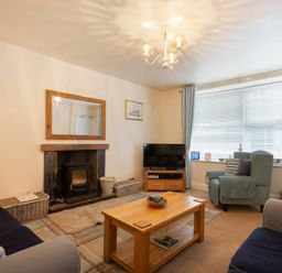 A living room with armchairs a coffee table a television and a fireplace at Lobster Pot Cottage in Seahouses