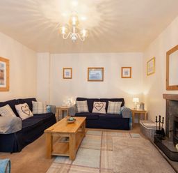 A living room with two sofas a coffee table a fireplace and wall art at Lobster Pot Cottage in Seahouses