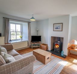 A living room with a sofa a TV a fireplace and wooden furniture at Beachward in Embleton