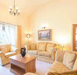 A living room with sofas wooden coffee table and a painting on the wall at Lavender Cottage Village Farm in Seahouses