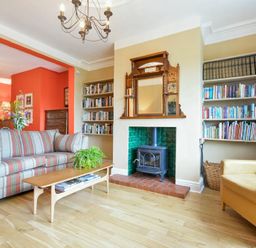 A living room with striped sofa coffee table plants wood stove and bookshelves at Estuary View in Alnmouth