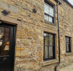 An exterior wall of a stone house with windows and a door at Lavender Cottage (Bailiffgate) Alnwick