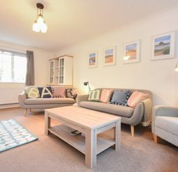 A living room with two sofas a coffee table an armchair a rug and framed pictures on the wall at Barmoor in Embleton