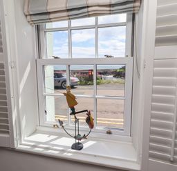 A window with a fishing figurine in the living room at Marie's Cottage in Craster