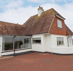 An exterior view of a house with white walls and a reddish-brown tiled roof at Whitestacks in Bamburgh