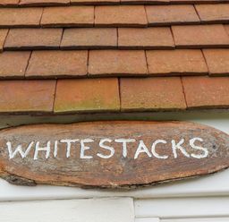 A wooden sign with the word Whitestacks under a tiled roof at Whitestacks Bamburgh