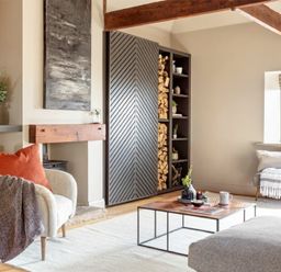 A living room with a cream armchair with cushion and throw a wood storage unit and a wooden coffee table with decorative items at Lantern View in Eglingham