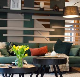 A living room with a green sofa yellow flowers on a coffee table and a hanging lamp at The Bolthole in Eglingham