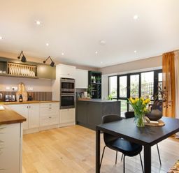 A kitchen with a black dining table and chairs next to large windows with curtains at The Bolthole in Eglingham