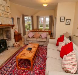 A living room with sofas a wooden coffee table and a stone fireplace at Armstrong Cottages No2 in Bamburgh