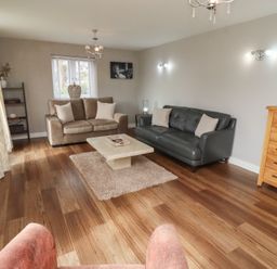 A living room with two sofas a coffee table and wooden chest of drawers at Assisi Apartment in Alnmouth
