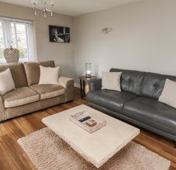 A living room with two sofas a coffee table and a window at Assisi Apartment in Alnmouth