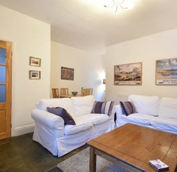 A living room with white sofas wooden coffee table and dining area at Crier Cottage in Alnwick