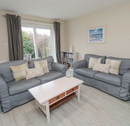 A living room with two grey sofas and a white coffee table at Curlew Cottage in Seahouses