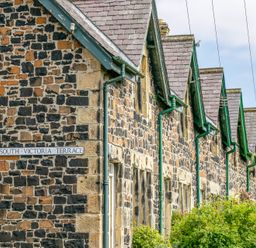 A row of stone terraced houses with green gutters and slate roofs at South Victoria Terrace