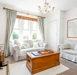 A living room with two sofas a wooden chest coffee table a chandelier and a framed map on the wall at Elliot Cottage in Bamburgh