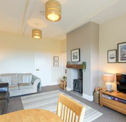 A living room with two sofas a wood burning stove and a television at Bellshill Cottage in Belford