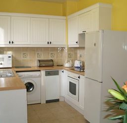 A kitchen with white cabinets appliances countertop and a bouquet of flowers at Briar Cottage in Town Yetholm and Kirk Yetholm